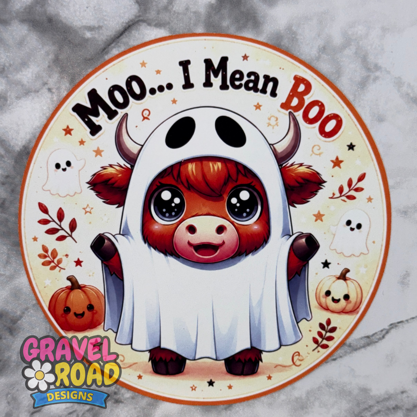 Round Halloween cow freshie cardstock design featuring a cute red highland cow dressed as a ghost under a white sheet. The top text reads “Moo… I Mean Boo” in bold black and orange lettering. The background has a soft cream fall theme with stars, tiny ghosts, pumpkins, leaves, and orange accents. A Gravel Road Designs watermark appears on the lower left side.