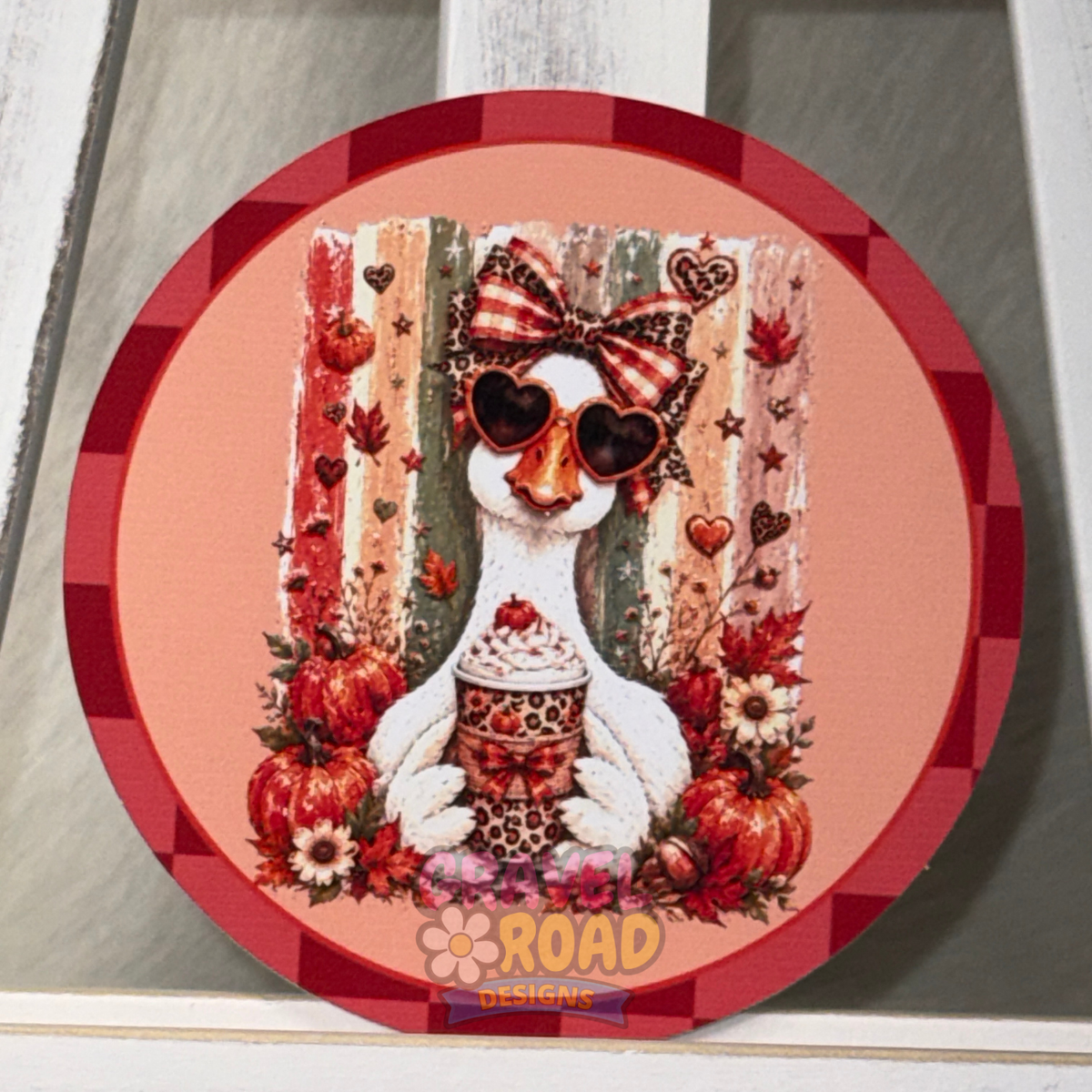 Round fall cardstock featuring a white goose wearing heart-shaped sunglasses and a patterned bow, surrounded by pumpkins and autumn leaves.