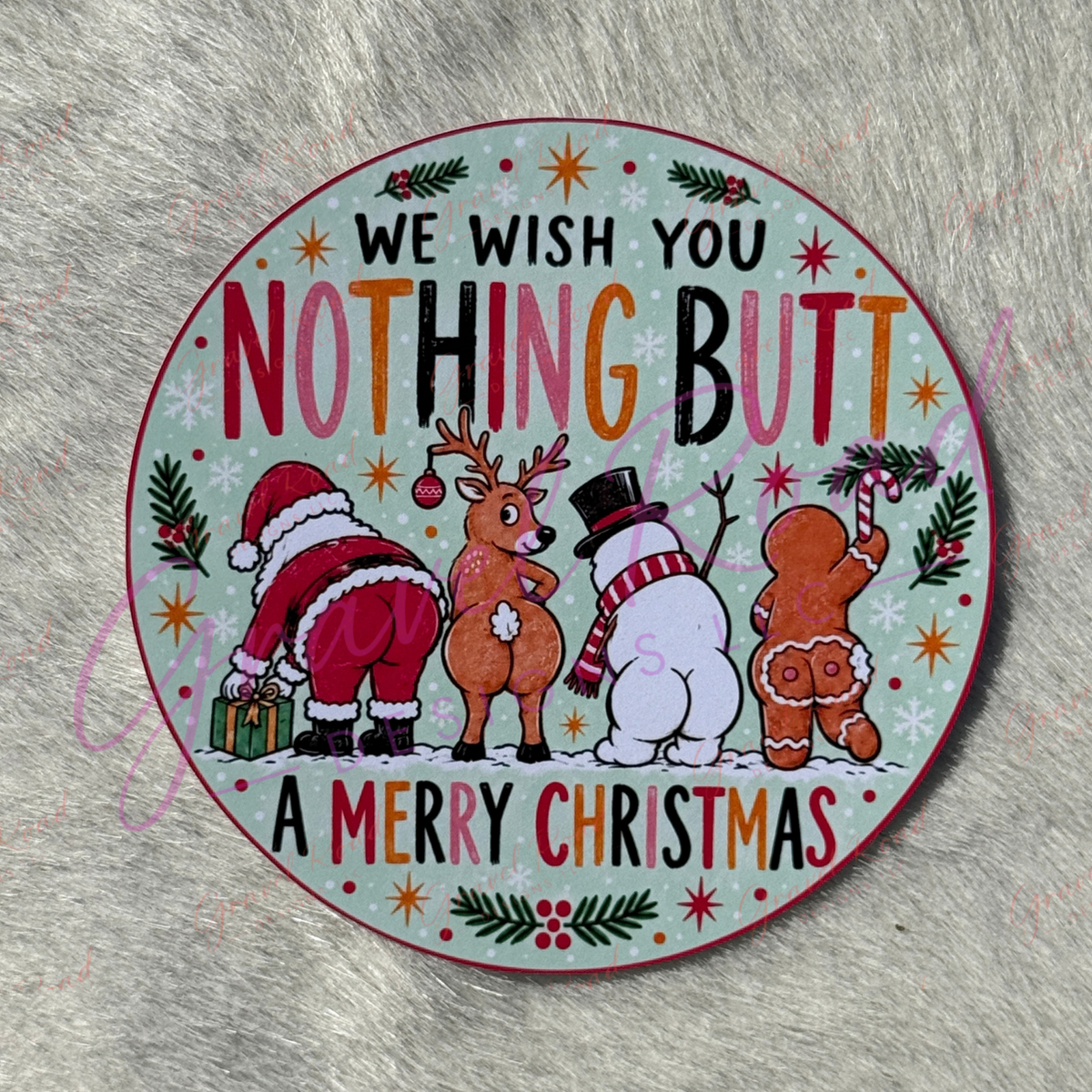 A round Christmas-themed cardstock with a humorous message reading 'WE WISH YOU NOTHING BUTT A MERRY CHRISTMAS' and featuring cartoon illustrations of Santa Claus, a reindeer, a snowman, and a gingerbread man on a pale mint background. Displayed on a faux fur background.