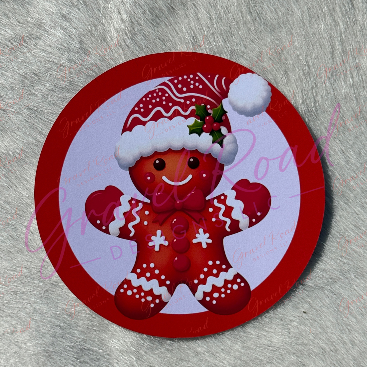 A round Christmas gingerbread cardstock featuring a smiling red gingerbread man wearing a Santa hat, displayed on a textured gray background.