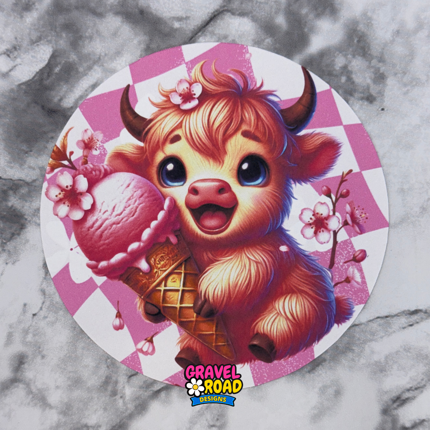 Circular design with a cartoon cow holding an ice cream cone on a pink checkered background, featuring the Gravel Road Designs logo.