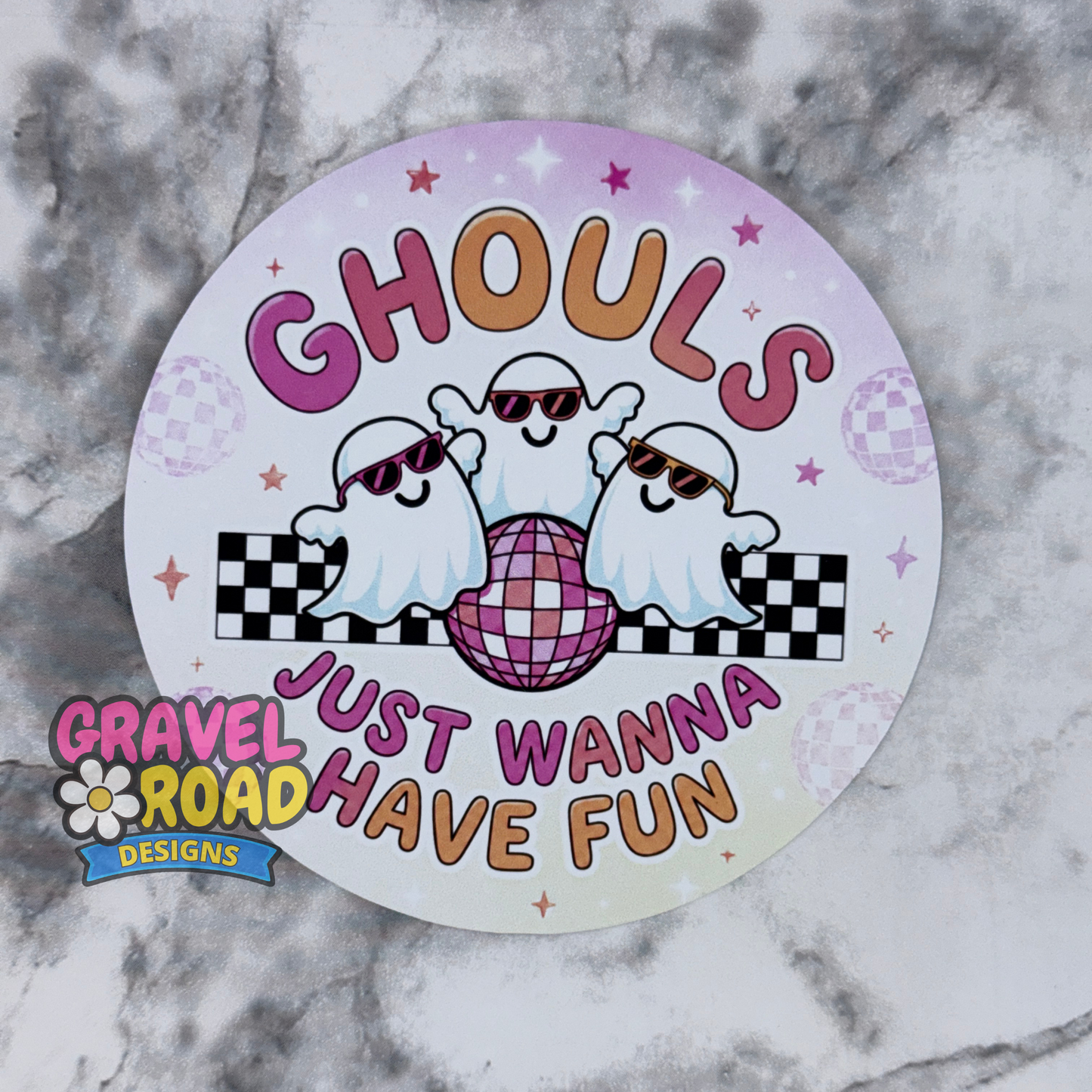 A cardstock with a Halloween theme, featuring three cartoon ghosts wearing sunglasses around a pink disco ball with the text 'GHOULS JUST WANNA HAVE FUN'. The sticker is displayed on a gray and white marble surface, with a 'Gravel Road Designs' logo overlay in the bottom left corner.