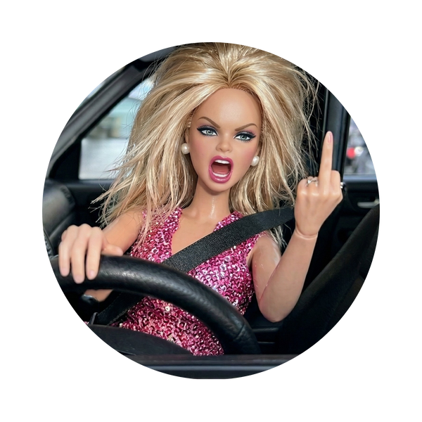 A circular inset photo of a blonde fashion doll with blue eyes wearing a pink glittery dress, sitting in a car and gesturing with her middle finger, shown on a white background.