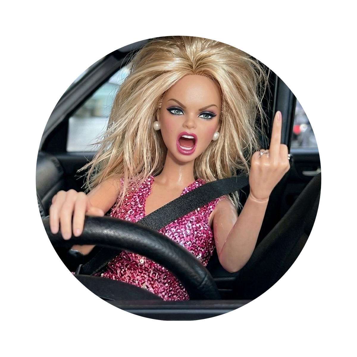 A circular inset photo of a blonde fashion doll with blue eyes wearing a pink glittery dress, sitting in a car and gesturing with her middle finger, shown on a white background.