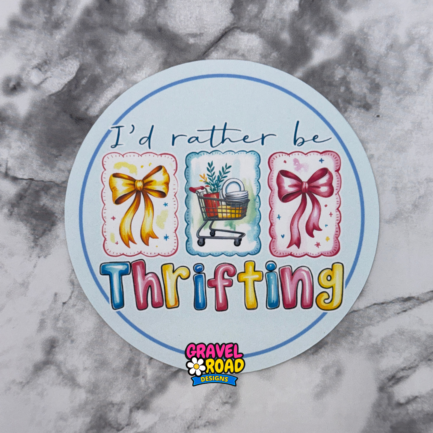 Round cardstock printed with 'I'd rather be Thrifting' text and shopping cart and bow designs on a marble background.