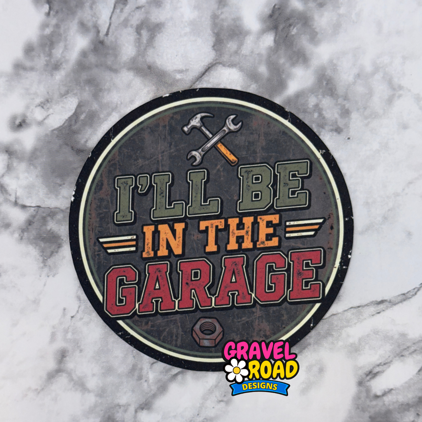 Round cardstock with 'I'll be in the garage' text on a marble background, featuring Gravel Road Designs logo.