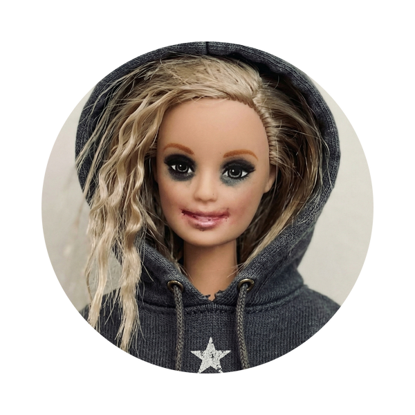 A doll with long wavy blonde hair wearing a dark gray hoodie with a silver glittery star on the front, shown inside a circular frame against a light gray background.