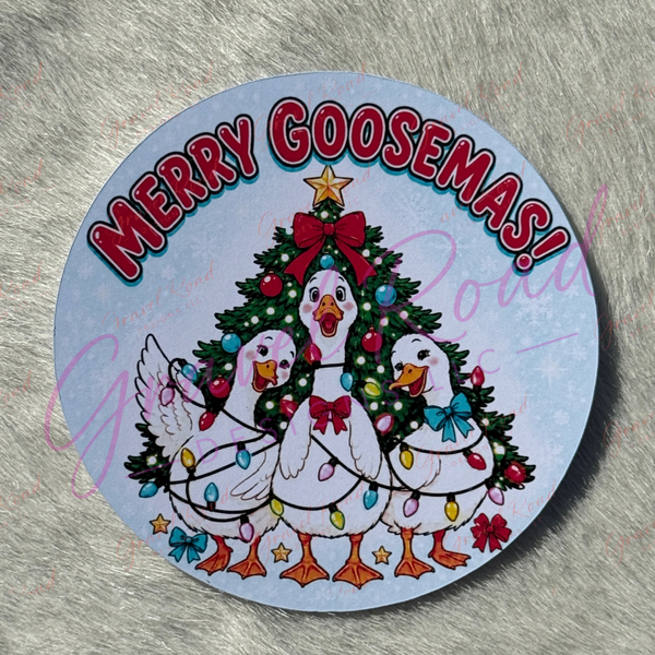A round printed cardstock featuring three white cartoon geese around a decorated Christmas tree, with the text “MERRY GOOSEMAS!” in red arched letters on a pale blue background. Displayed on a faux fur background.