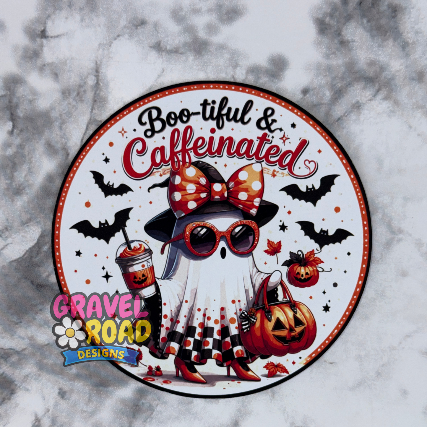 Circular design with a cartoon ghost character wearing a witch hat and sunglasses, holding a coffee cup and pumpkin, with text 'Boo-tiful & Caffeinated' on a gray marble background.