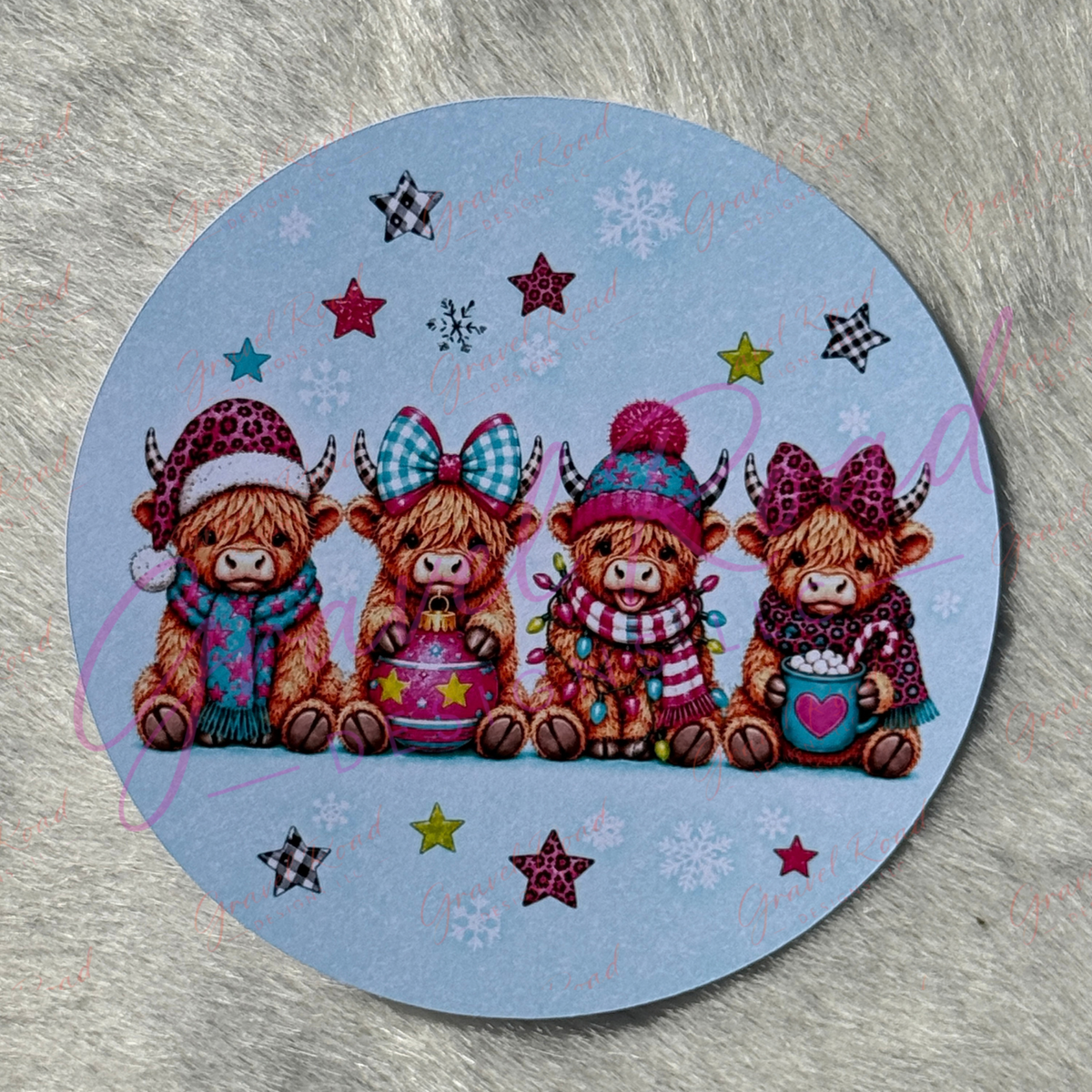 A round cardstock featuring four cute Highland cows in winter clothing, displayed on a textured gray surface.