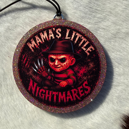Cartoon horror inspired character freshie with a glittery circular border, black hanging cord, and “Mama’s Little Nightmares” text on a red splatter background.