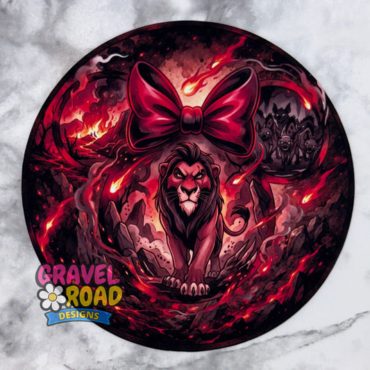 A circular cardstock featuring a dark fantasy illustration of a lion under a large red bow, surrounded by fiery red and black swirls. The Gravel Road Designs logo is visible in the bottom-left corner. On a grey marble backdrop.