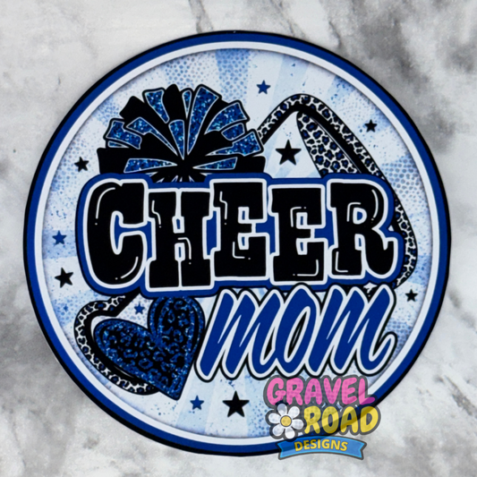 A circular cardstock design featuring the words 'CHEER mom' in bold black and blue lettering, decorated with a blue leopard-print pom-pom, a blue leopard-print heart, and small stars on a light blue patterned background. The design includes a 'Gravel Road Designs' logo at the bottom.