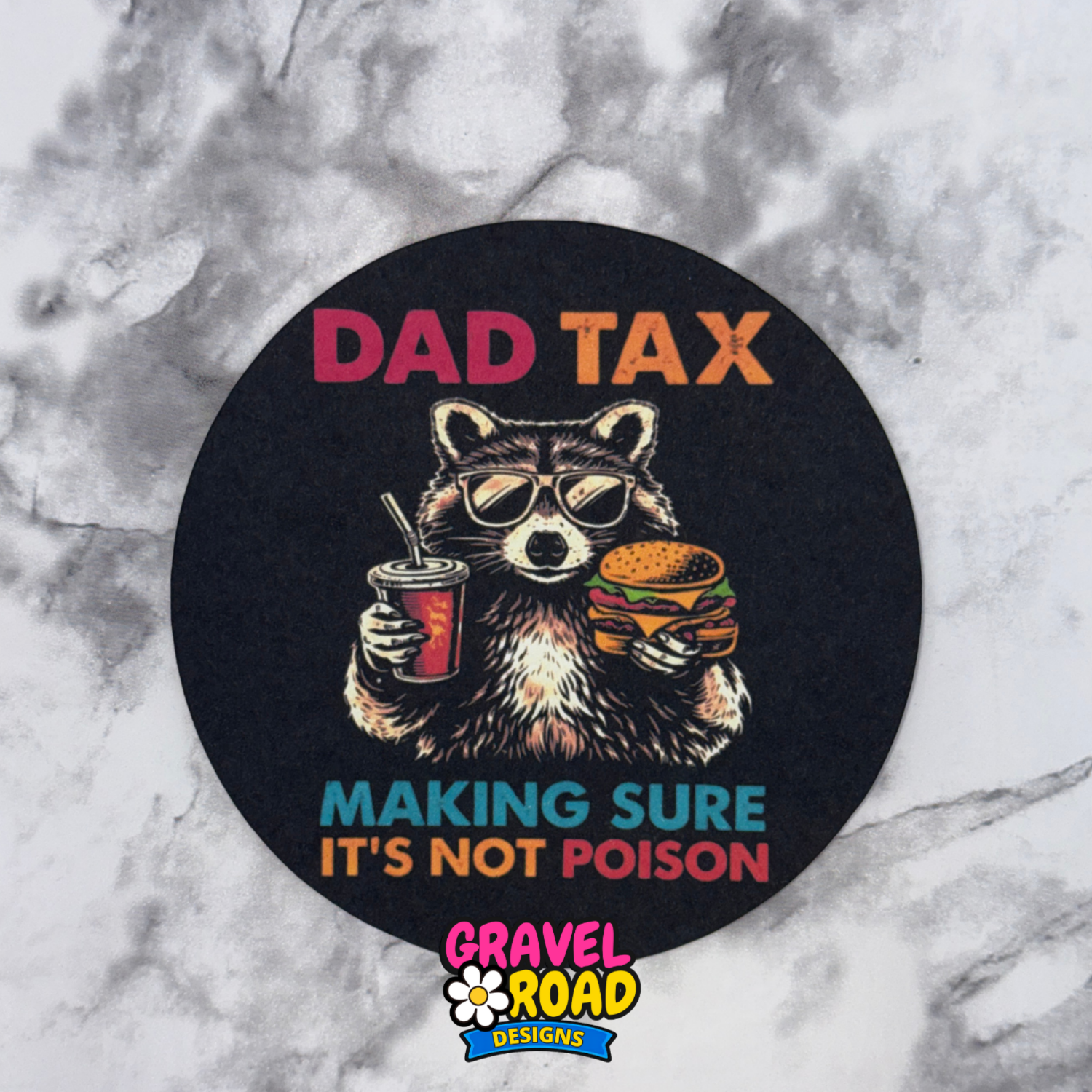 Round black cardstock with a raccoon holding a drink and burger, text 'Dad Tax Making Sure It's Not Poison' and 'Gravel Road Designs' logo on a marble background.