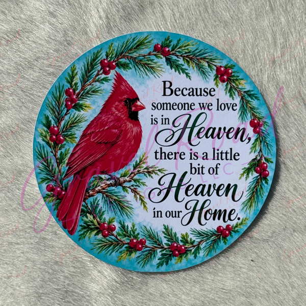A round cardstock featuring a red cardinal bird, green pine branches, red berries, and black script text 