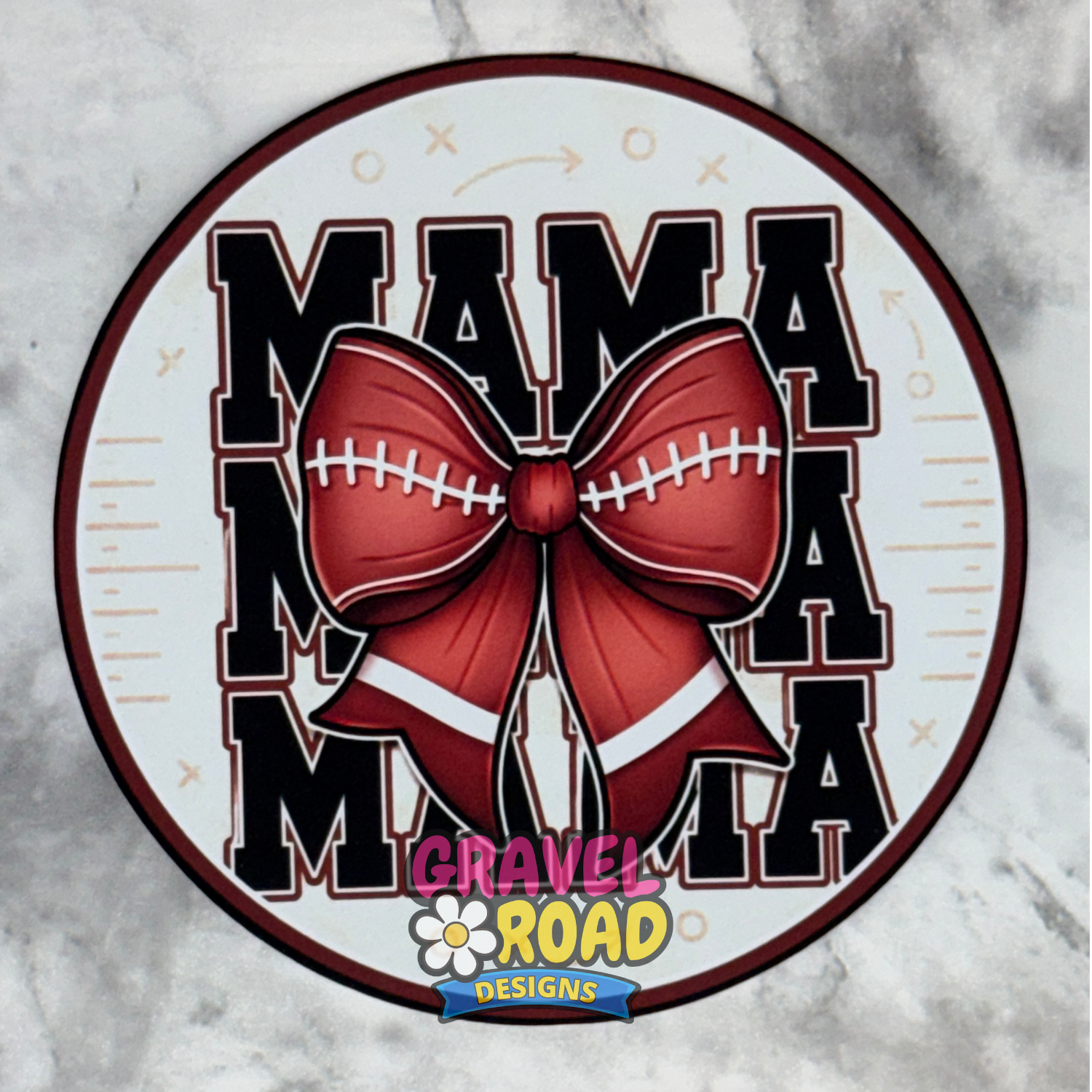 A circular cardstock design featuring the text 'MAMA' repeated vertically in black varsity-style letters with white outlines, overlaid with a large brown football bow with white laces. A 'Gravel Road Designs' logo is visible at the bottom center.