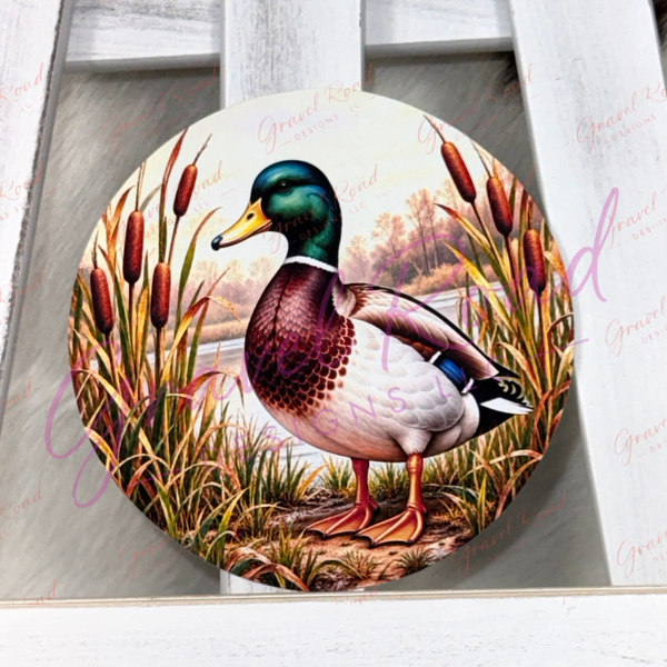 A round cardstock featuring a detailed illustration of a mallard duck standing among cattails, displayed on a white wooden ladder. The plaque has a subtle watermark overlay.