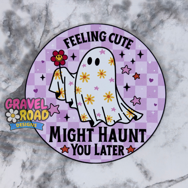 A circular cardstock with a purple checkered background, a cartoon ghost holding a flower, and the text 'FEELING CUTE MIGHT HAUNT YOU LATER.' A Gravel Road Designs logo appears on the left side.