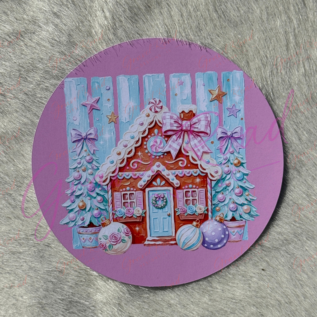 A round purple cardstock featuring a colorful Christmas gingerbread house illustration, displayed on a gray textured faux fur surface.