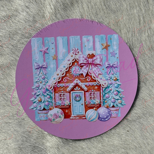A round purple cardstock featuring a colorful Christmas gingerbread house illustration, displayed on a gray textured faux fur surface.