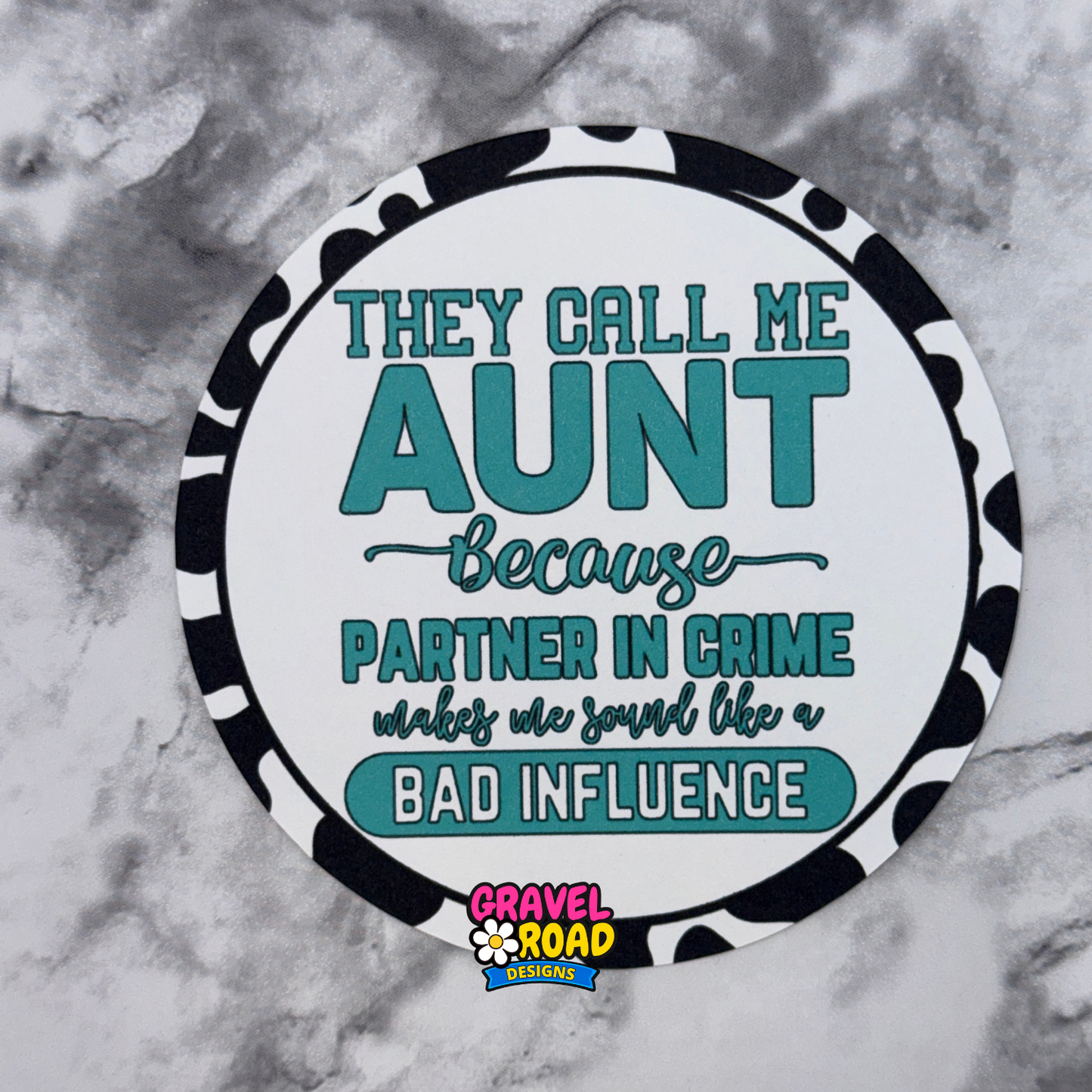 Round cardstock with text 'They call me aunt because partner in crime makes me sound like a bad influence' on a marble background.