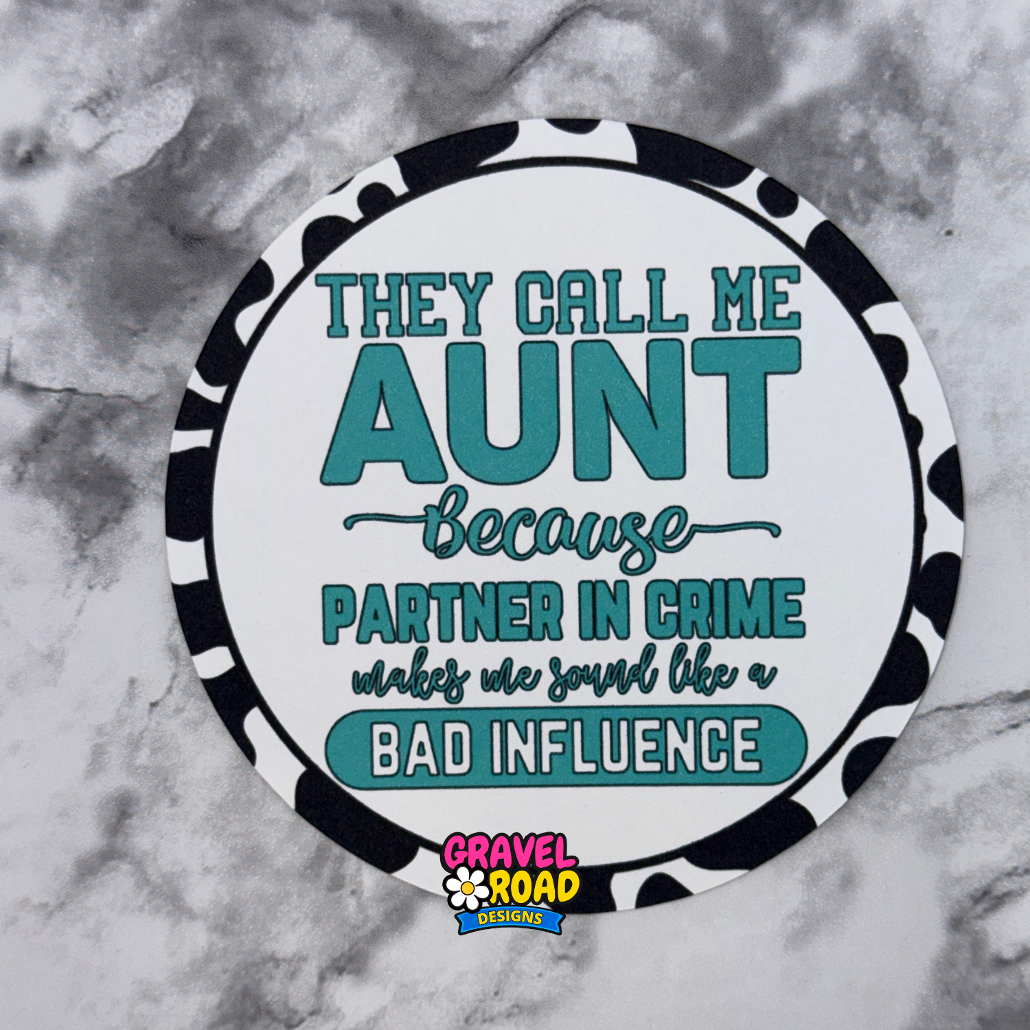 Round cardstock with text 'They call me aunt because partner in crime makes me sound like a bad influence' on a marble background.