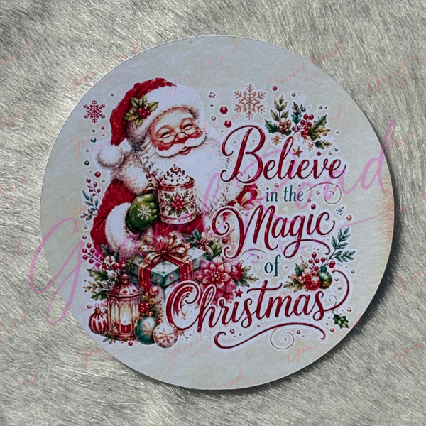 A Christmas cardstock of Santa Claus holding a holiday‑themed mug, surrounded by wrapped gifts, ornaments, holly, berries, lanterns, and snowflakes, with the phrase “Believe in the Magic of Christmas” displayed across the design. Displayed on a faux fur background.