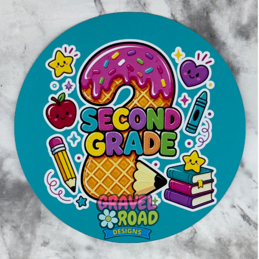 A round turquoise cardstock featuring a colorful 'Second Grade' school-themed design with a waffle cookie, pink donut, pencil, apple, crayon, books, and stars on a marble background.