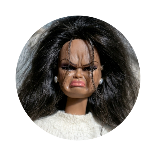 A close-up circular photo of a doll with a distressed, angry expression, wearing a cream knit top and small pearl-like earrings, isolated on a black background.