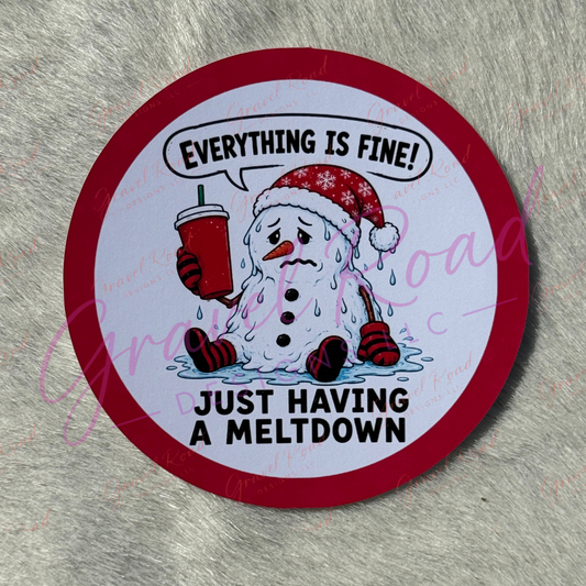 A circular cardstock with a red border and a cartoon snowman holding a red drink, with the text 'EVERYTHING IS FINE! JUST HAVING A MELTDOWN' on a gray faux-fur background.