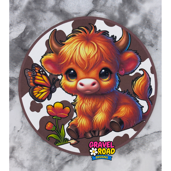 Colorful cartoon cow with a butterfly and flowers on a circular cardstock with 'Gravel Road Designs' logo.