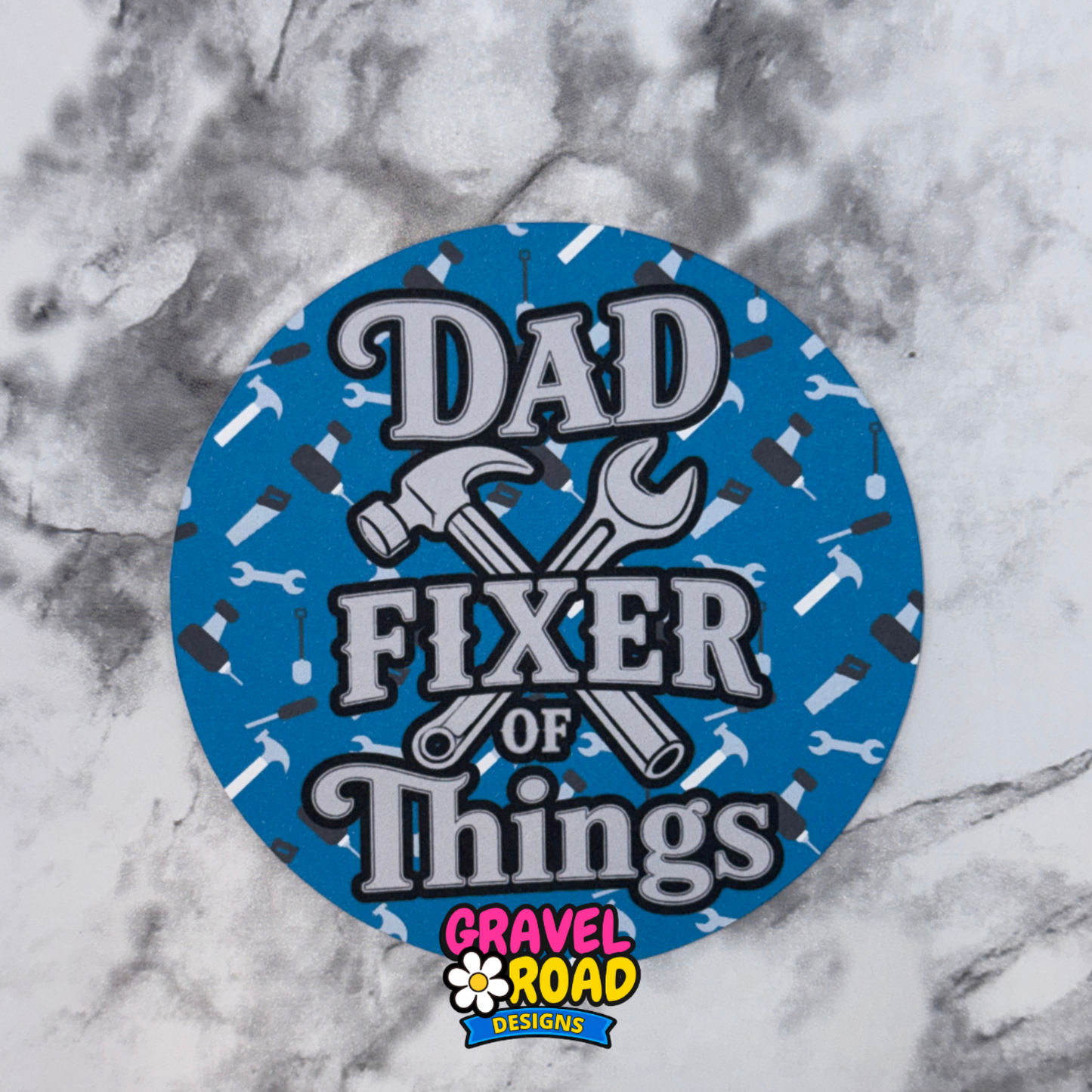 Round blue cardstock with 'Dad Fixer of Things' text and Gravel Road Designs logo on a marble background