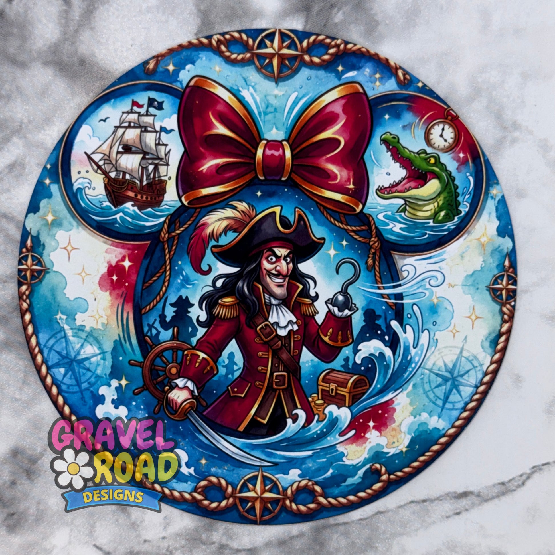 A circular pirate-themed cardstock featuring a central cartoon pirate with a large red bow, blue ocean waves, a ship, an alligator, and compass motifs, shown on a light marble-patterned background. The Gravel Road Designs logo appears in the lower left. On a grey marble backdrop.